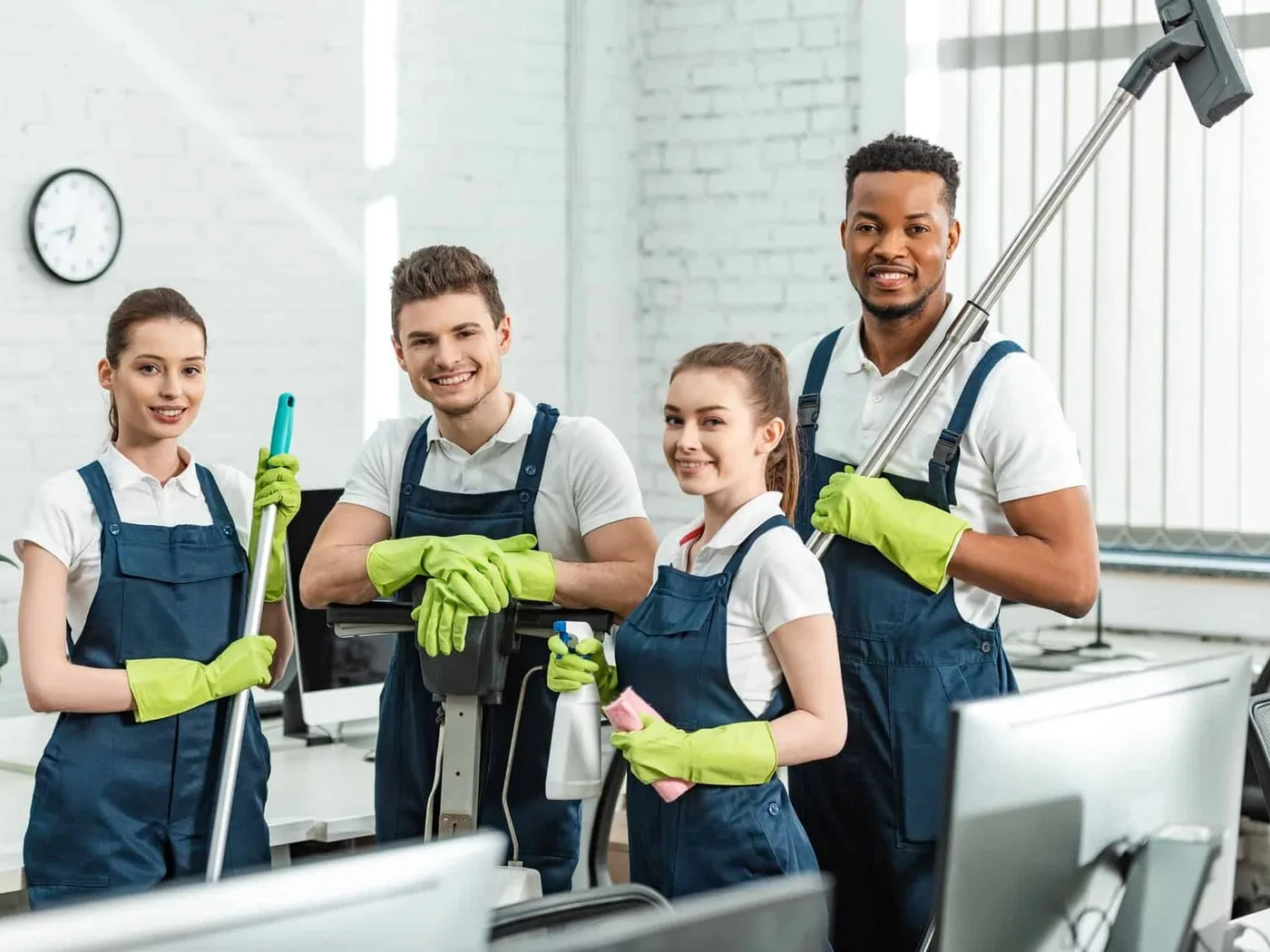 Four members of a cleaning team with their equipment in an office