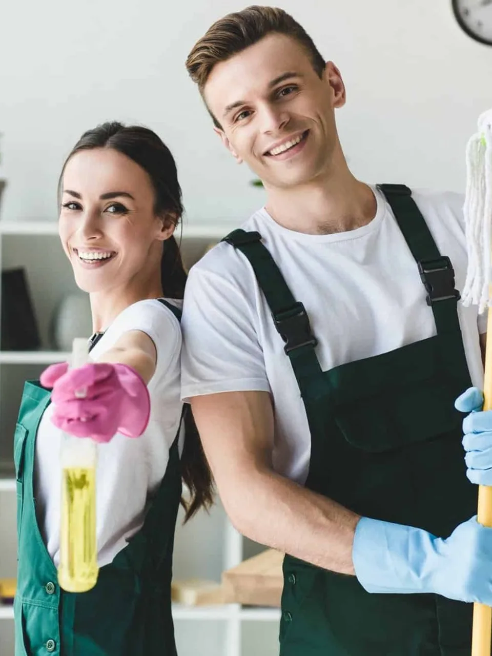 Two cleaners with a mop and spray bottle, smiling at the camera