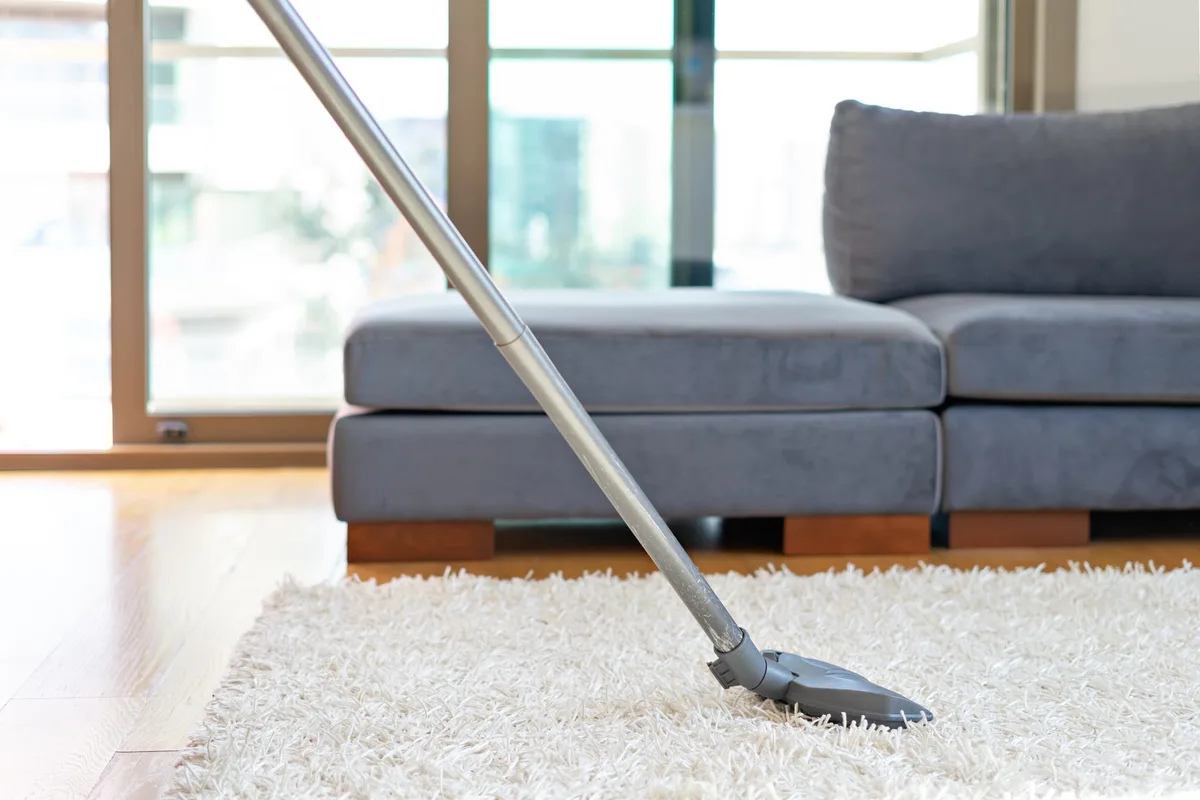 A vacuum cleaning a white rug in a modern living room