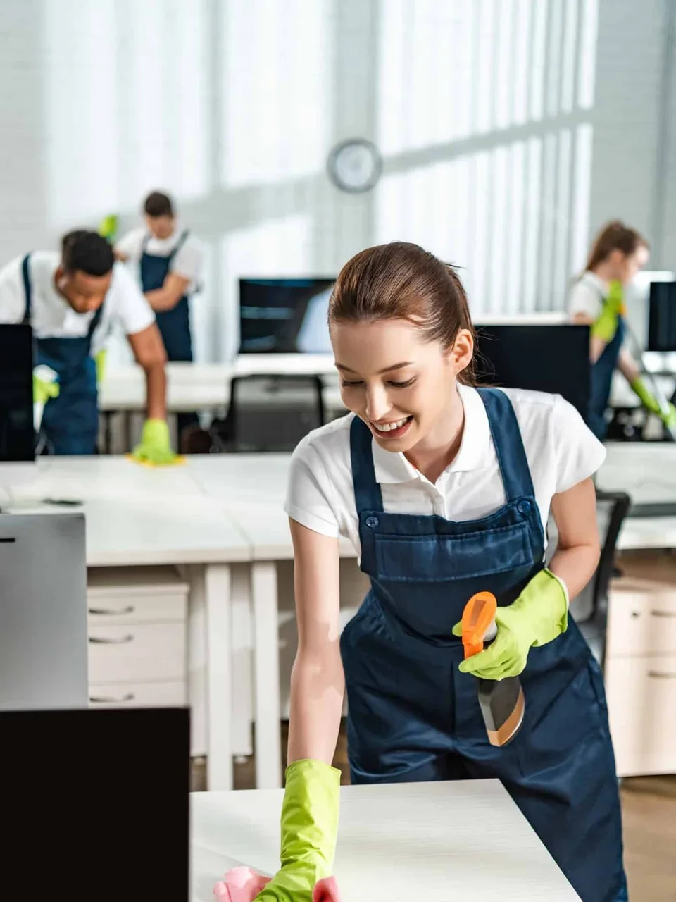 A cleaner wiping down a desk in an open-plan office
