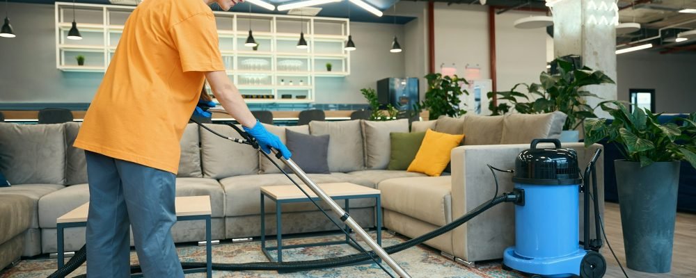 Cleaning company worker cleans a carpet in a recreation area
