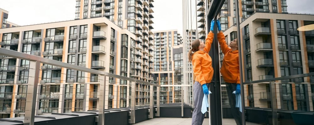 Cleaning lady cleans windows office center she is in comfortable uniform