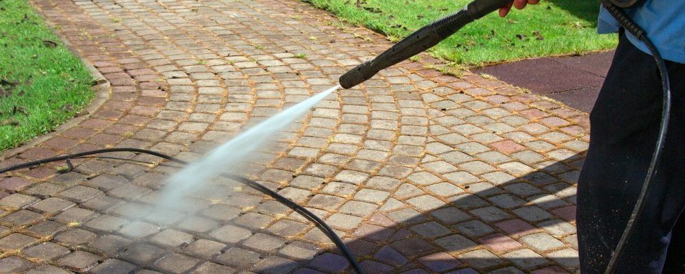 Cleaning street with high pressure power washer, washing stone garden paths