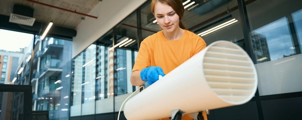 Woman installs ozone generator on office desk in coworking area